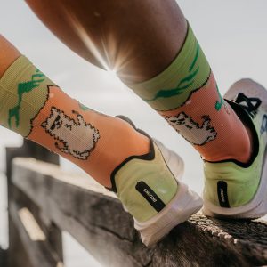 modèle lamalou chaussette sport les raymondes sur un coureur an gros plan chaussettes avec un lama couleur saumon et vert, techniques et respirantes adaptée au trail running crossfit fitness rando...